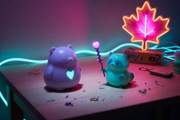 Two kawaii 3D-printed figurines in synthwave neon on a Quebec desk, each with a different silhouette cue
