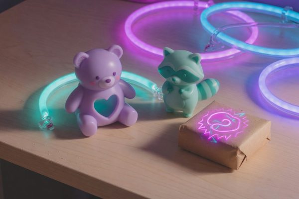 Two kawaii 3D-printed figurines in synthwave neon beside a sealed parcel with an abstract prepaid-duty seal